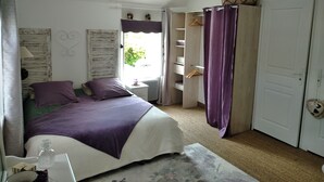 Een slaapkamer met een bed, nachtkastje, kast en raam met gordijnen.