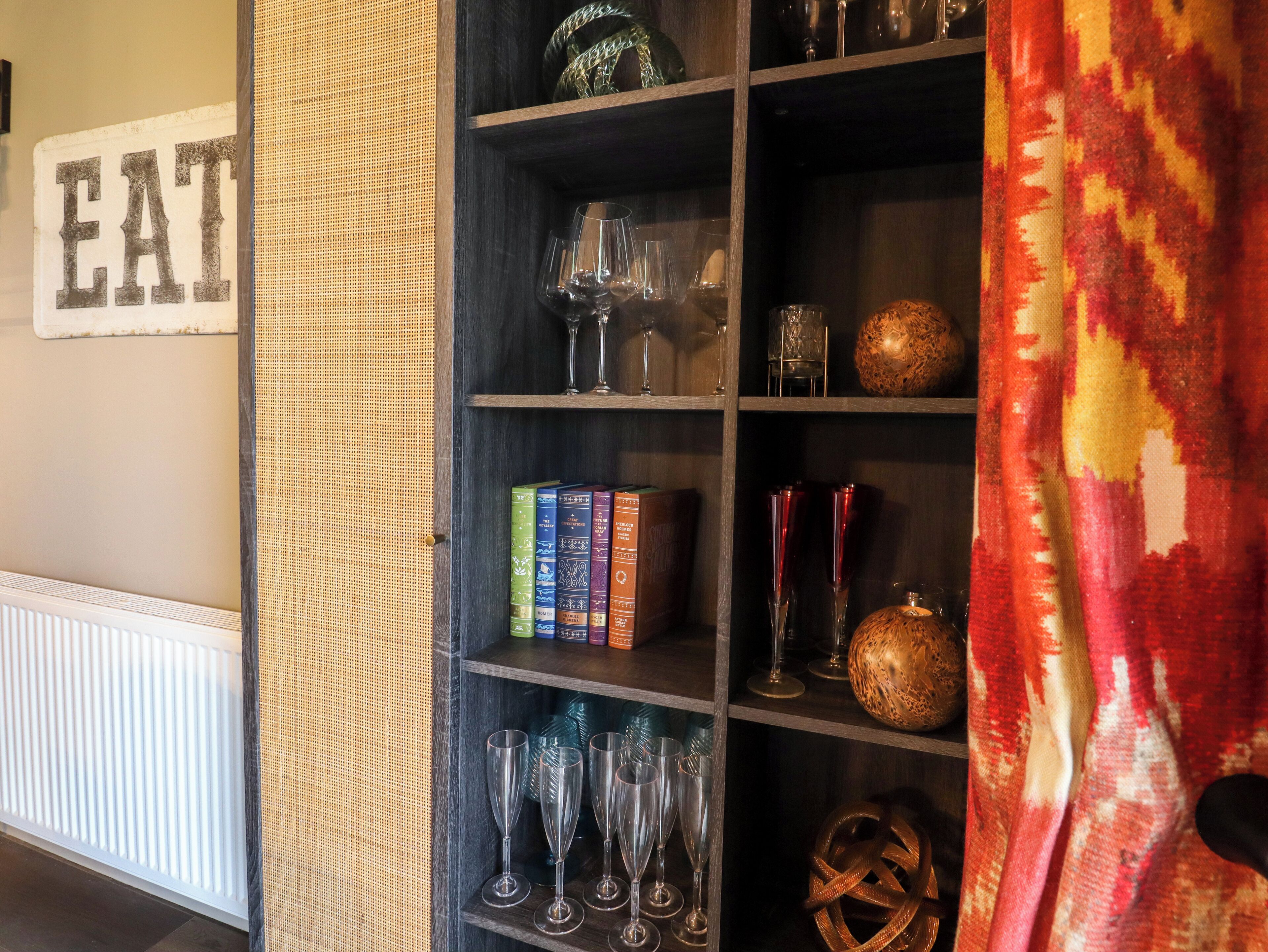 A bookshelf with books, wine glasses, and decorative items.