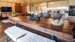 Un salón amplio con una gran mesa de madera para comer, asientos cómodos y electrodomésticos de cocina modernos.