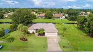 A suburban house with a front yard, driveway, and a small pond.
