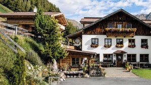 A traditional chalet-style building with a wooden facade, large windows, and a balcony with flower boxes. - Das Eppensteiner (Navis)