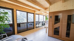 A modern interior with large windows, wooden ceiling beams, and a seating area with tables. - Das Eppensteiner (Navis)