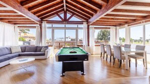 Un grand espace de vie comprenant une table de billard, un canapé et une table à manger avec des chaises.