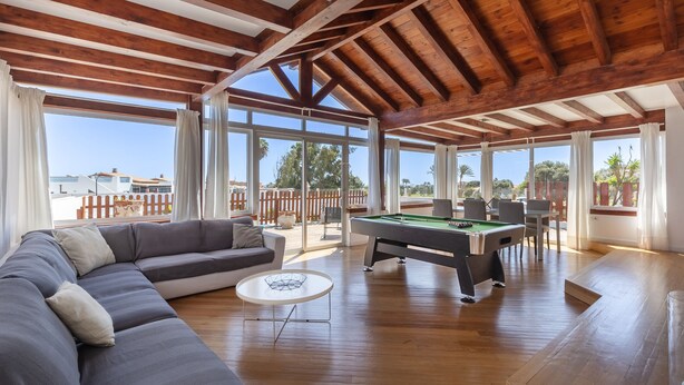 Une pièce spacieuse équipée d’une table de billard, d’un canapé et de grandes fenêtres donnant sur l’extérieur.