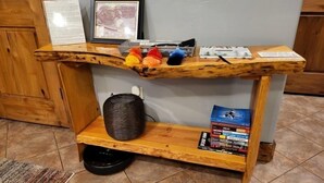Uma mesa de madeira com uma prateleira, um quadro emoldurado e uma cesta.