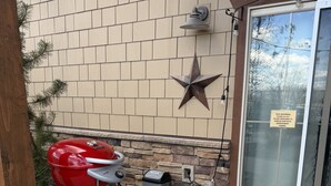 Churrasqueira do lado de fora de um edifício com parede de pedra, decoração em forma de estrela e porta com um letreiro.