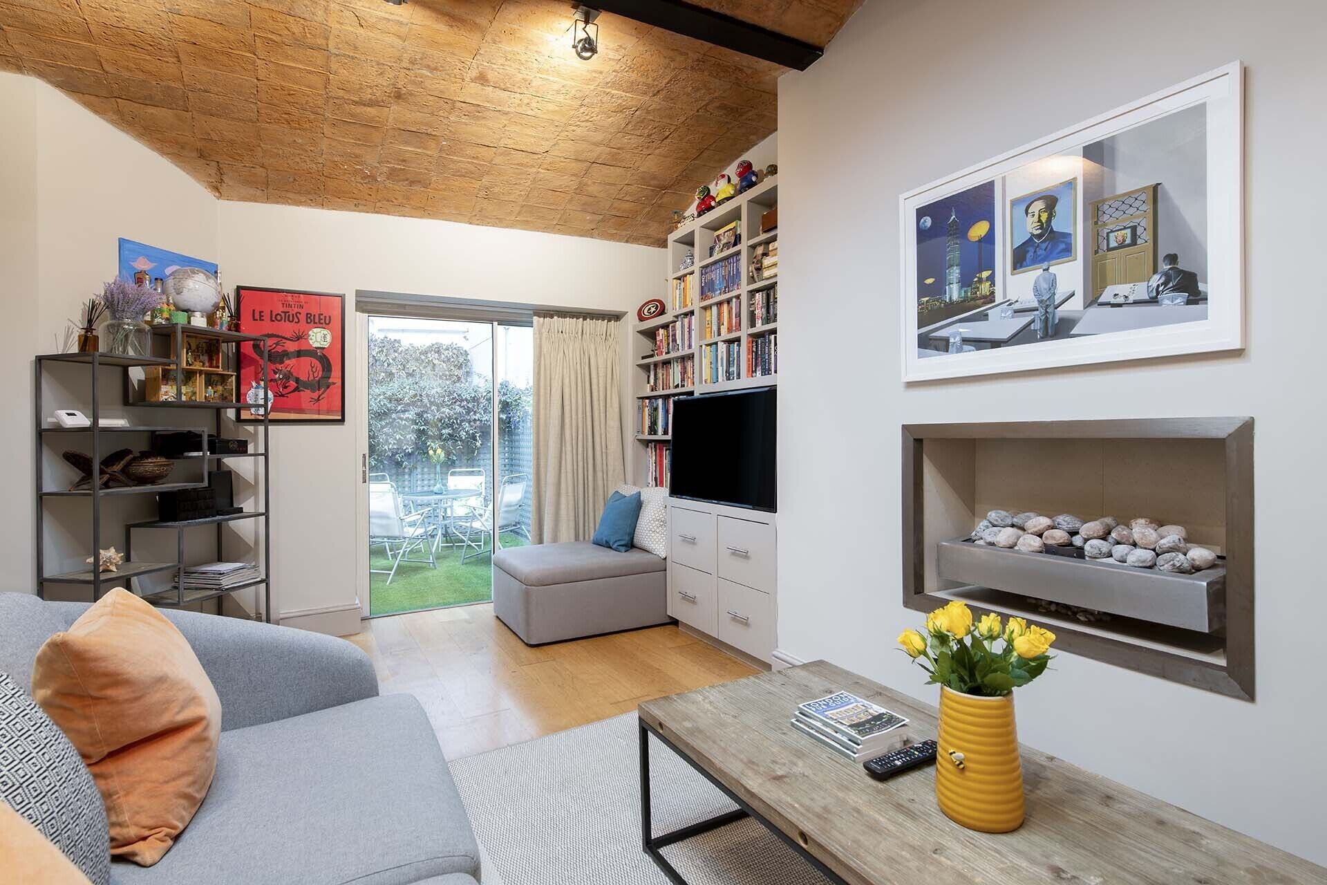 A living room with a sofa, a coffee table, a bookshelf, a TV, and a fireplace.