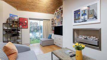 A living room with a sofa, a coffee table, a bookshelf, a TV, and a fireplace.