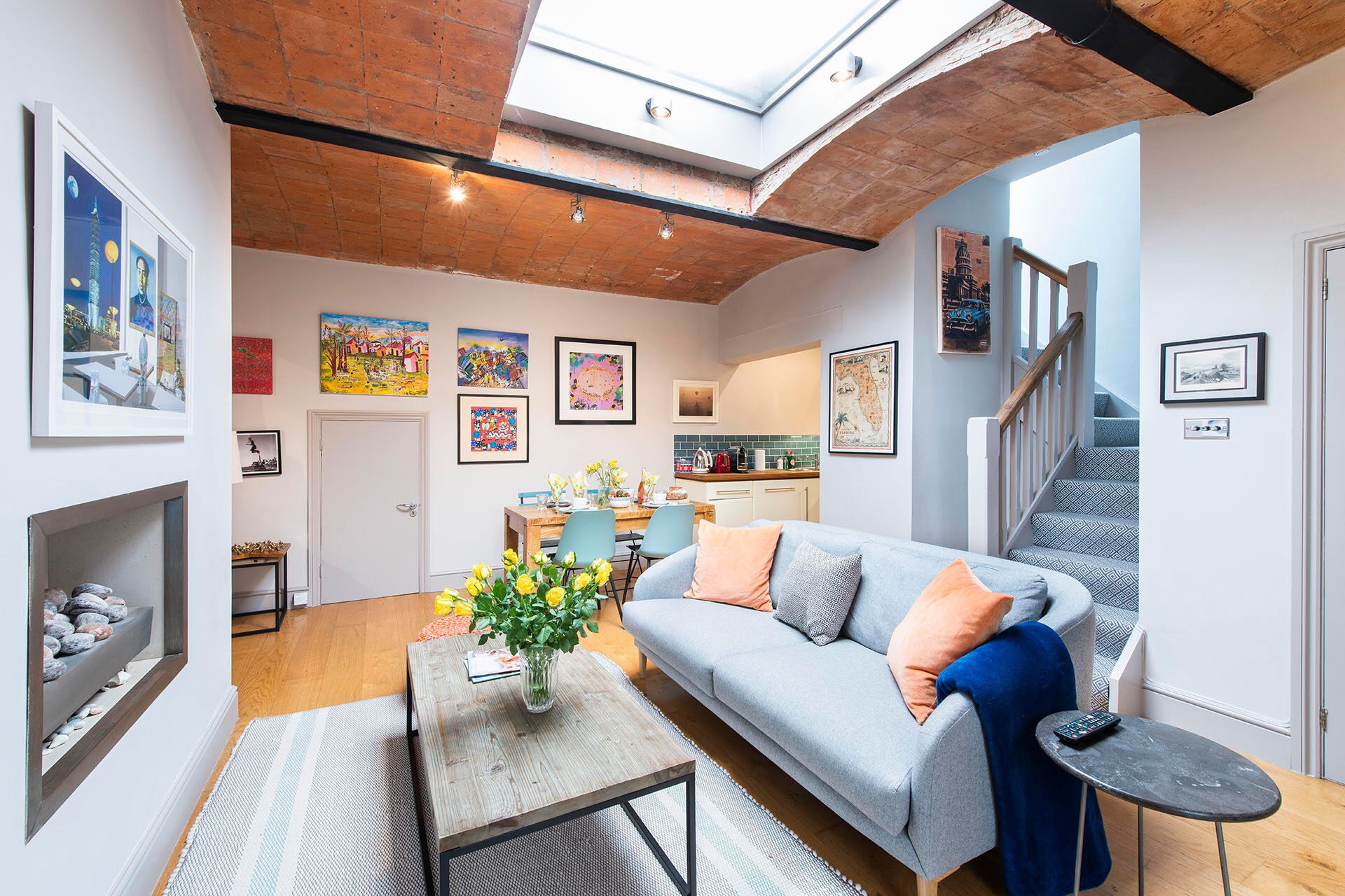 A modern living room with a loft-style ceiling, a sofa, a coffee table, and a dining area.