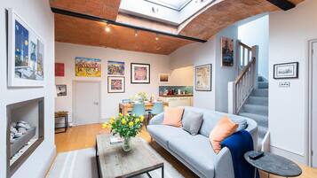 A modern living room with a loft-style ceiling, a sofa, a coffee table, and a dining area.