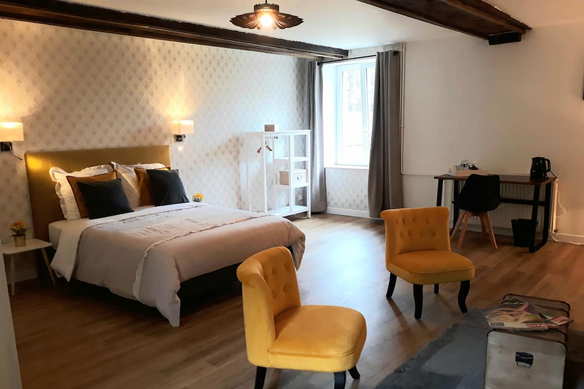 Une chambre à coucher avec un lit, deux chaises, un bureau et un radiateur.