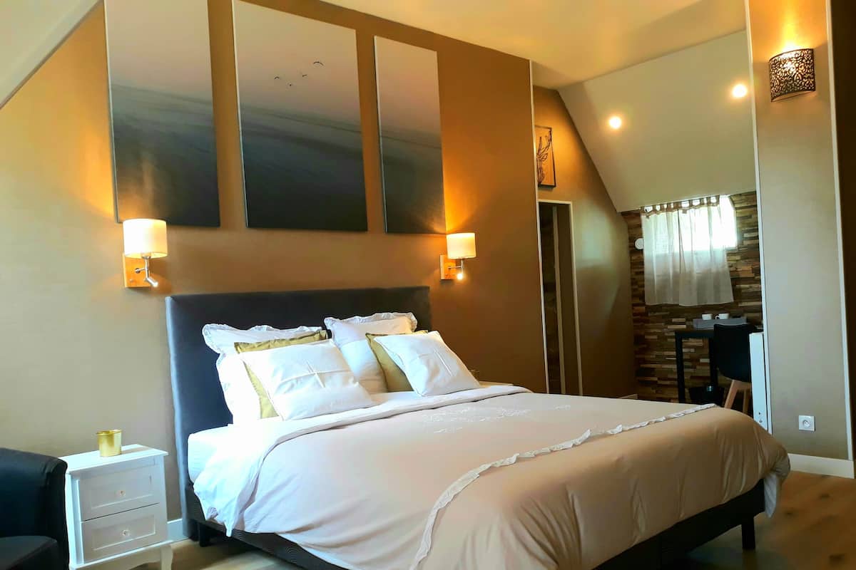 Une chambre à coucher avec un grand lit, deux tables de chevet, une commode, un bureau et une chaise.