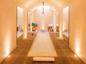 A spa corridor with a central massage table, mirrors on the walls, and a plant. - La Valise San Miguel de Allende, Member of Small Luxury Hotels (San Miguel de Allende)