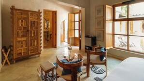 A spacious room with a large wooden cabinet, a dining area with chairs and a table, and a large window providing a view of the outside. - La Valise San Miguel de Allende, Member of Small Luxury Hotels (San Miguel de Allende)