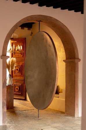 Traditional charm fills this room, featuring a large mirror, a geometric-patterned cabinet, and a vase with pampas grass.