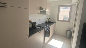 Una cocina moderna con suelo de madera clara, electrodomésticos de acero inoxidable y un ventanal que aporta luz natural.
