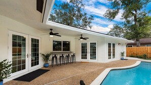 A house with a pool, a patio with chairs, and a bar area. - 15 Mins to Beach! Safe & Quiet Home Near Beach & Downtown~Heated Pool~Ping Pong/Foosball. (Fort Lauderdale)