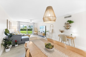 A modern living room with a dining table, sofa, and a large window.