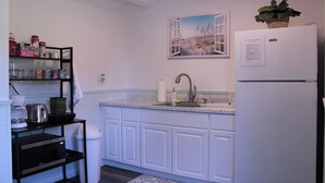 A kitchen with white cabinets, a black countertop, a white refrigerator, a sink, and a window with a view of a beach. - Beautiful new property, great location. (Waves)