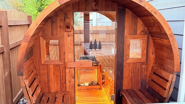 Ein hölzernes Whirlpool mit kreisförmigem Design, umgeben von einer Holzterrasse und einem Holzzaun.
