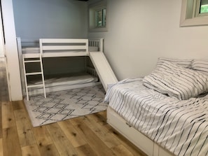 Um quarto com uma cama beliche, um tapete estampado e uma cama com roupa de cama listrada.