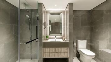 A modern bathroom with a glass shower enclosure, a sink with a mirror above, and a toilet.