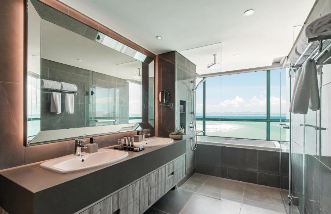 Een moderne badkamer met twee wastafels, een grote spiegel en een douche met glazen wanden.