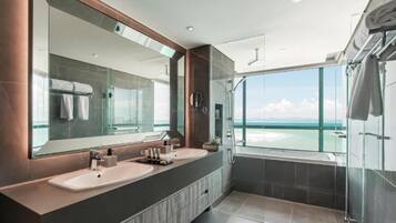Een moderne badkamer met twee wastafels, een grote spiegel en een douche met glazen wanden.