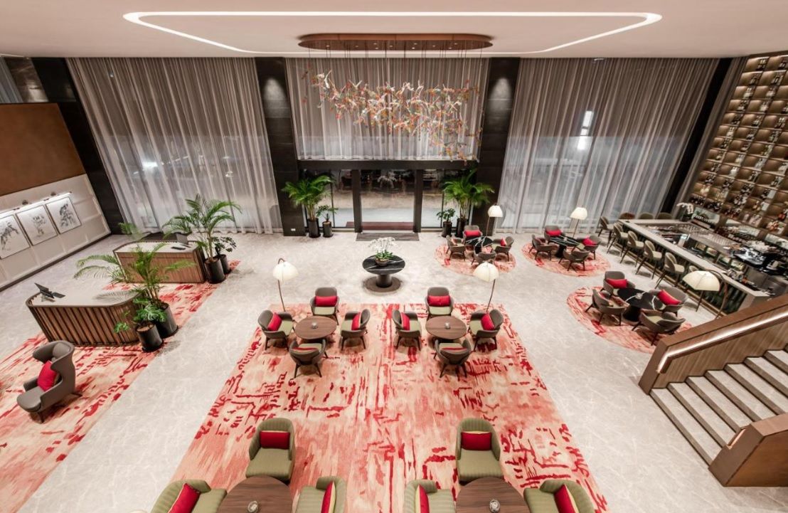 A spacious lobby with a central seating area, a staircase, and a large chandelier.