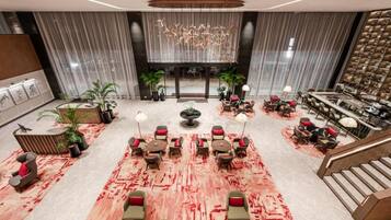 A spacious lobby with a central seating area, a staircase, and a large chandelier.