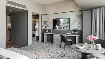 A modern hotel room with a dining area, a TV mounted on the wall, and a visible closet.