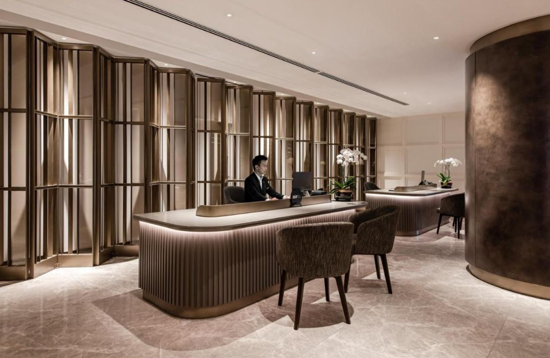 A reception desk with a modern design, a large pillar, and a seating area with chairs.