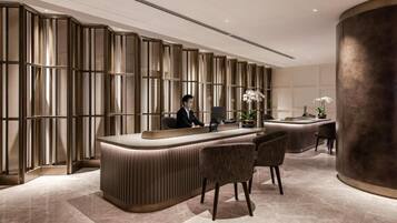 A reception desk with a modern design, a large pillar, and a seating area with chairs.