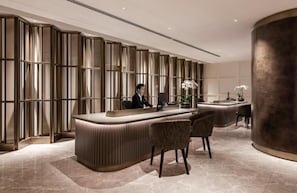 A reception desk with a modern design, a large pillar, and a seating area with chairs. - Ascott Gurney Penang (George Town)