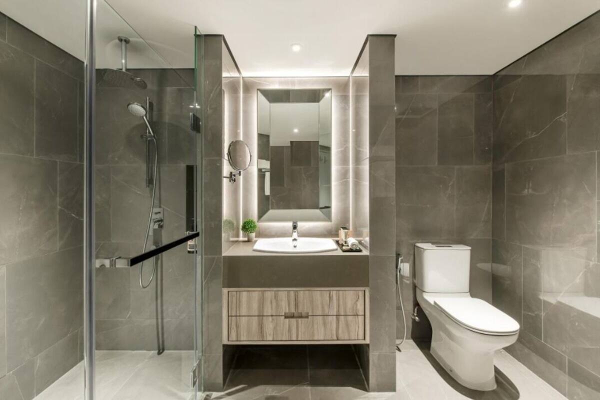 A modern bathroom with a glass shower enclosure, a sink with a mirror, and a toilet.