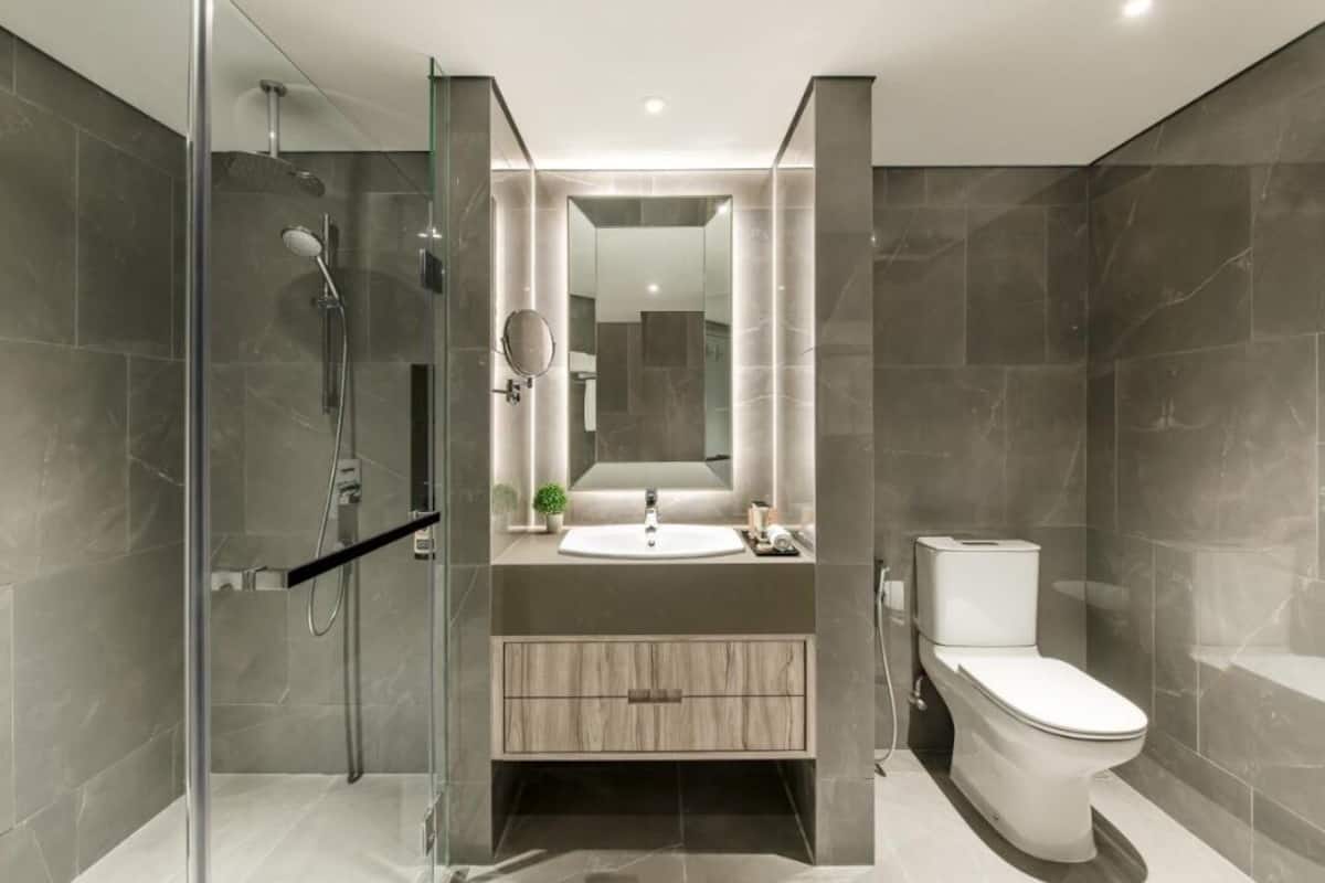 Un baño moderno con cabina de ducha de vidrio, un lavabo con espejo y un inodoro.