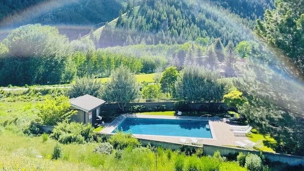 En swimmingpool omgivet af frodig vegetation og bjerge.
