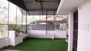 A balcony with artificial grass, a white bench, and a view of a red-roofed building.