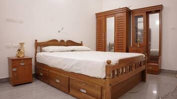 A bedroom with a wooden bed, a nightstand, a wardrobe, and a mirror.