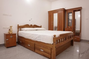 Une chambre à coucher avec un lit en bois, une table de chevet, une armoire et un miroir.
