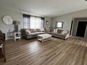 Ein Wohnzimmer mit einer Sofagarnitur, einem Couchtisch, einer Lampe und einer Wanduhr.