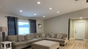 Una sala de estar con un sofá modular, una mesita y un otomán grande.