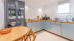 A modern kitchen with light blue cabinets, a wooden countertop, and a dining area with a round table and chairs. - Cosy 1 Bedroom Apartment Near Wimbledon Station (London)