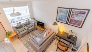 A modern living room with a sofa, coffee table, and artwork on the wall. - Cosy 1 Bedroom Apartment Near Wimbledon Station (London)