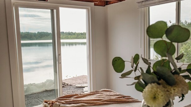Ein Zimmer mit großem Fenster und Seeblick, einer Holzbalkendecke und einem Bett mit Decke.