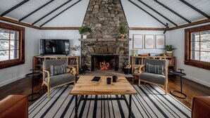 Ein gemütliches Wohnzimmer mit einem Kamin aus Stein, Holzmöbeln und einem Fernseher.