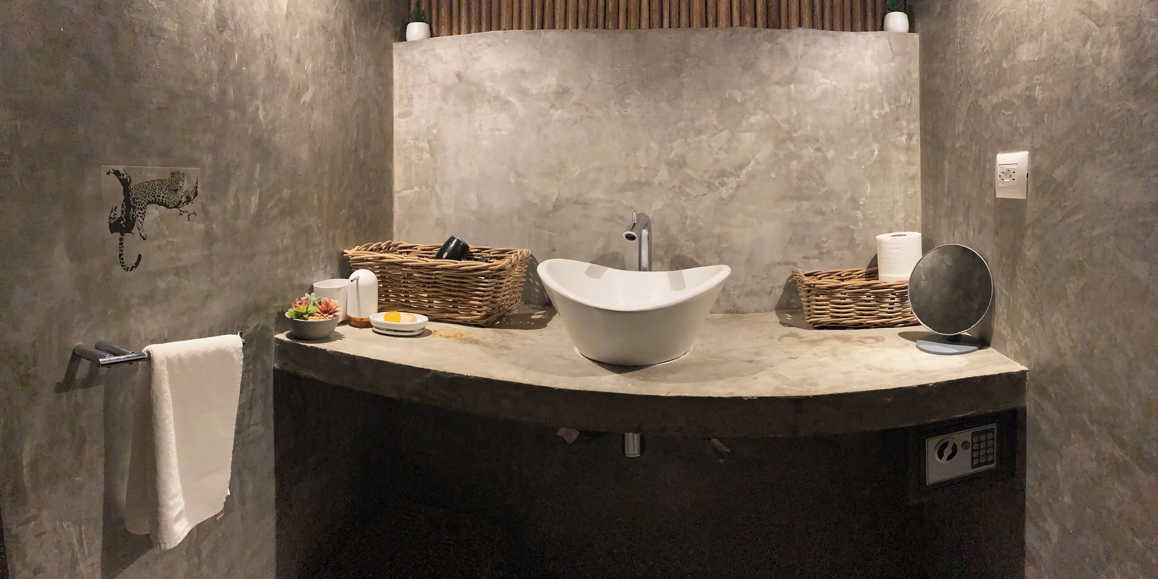 A bathroom with a curved sink, a towel rack, and two wicker baskets.