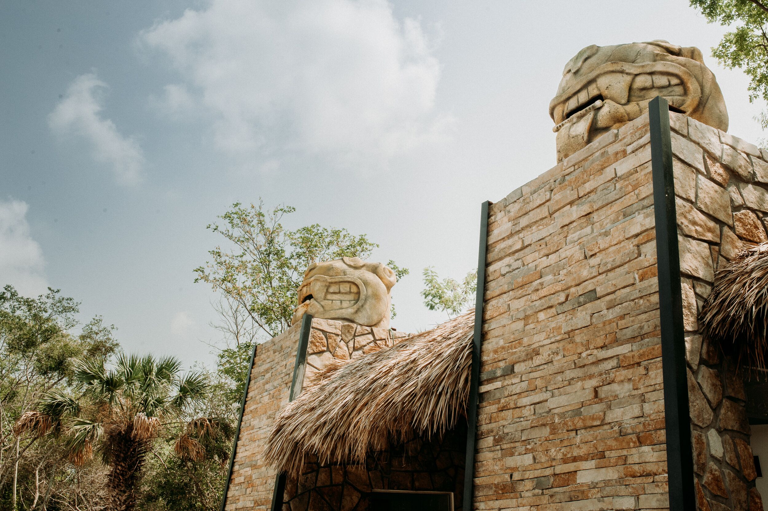 A building with a stone facade, a thatched roof, and a large stone head sculpture.