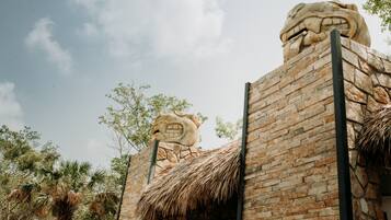 A building with a stone facade, a thatched roof, and a large stone head sculpture.