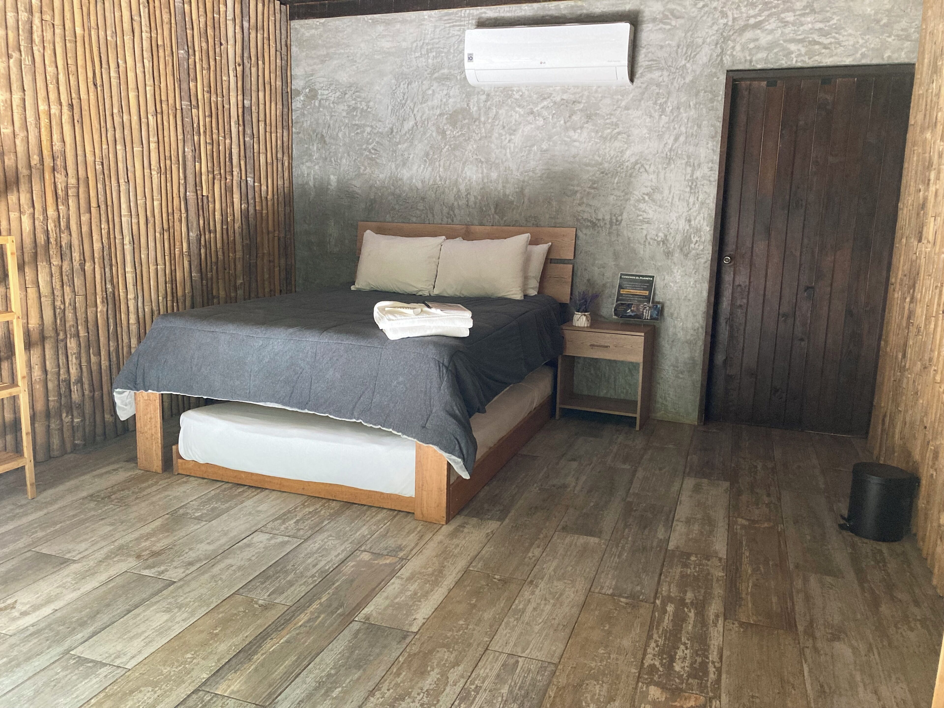 A bedroom with a bed, bedside table, and a wall-mounted air conditioner.
